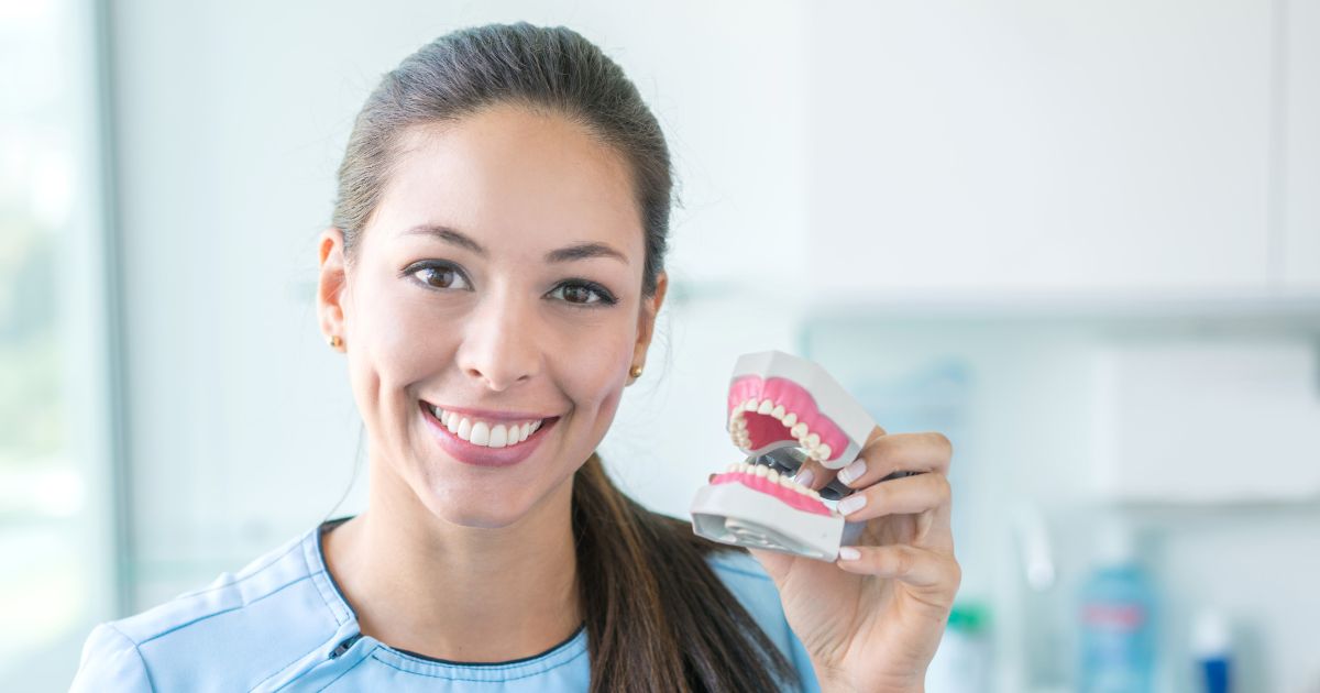 A dentist holding a denture in hand